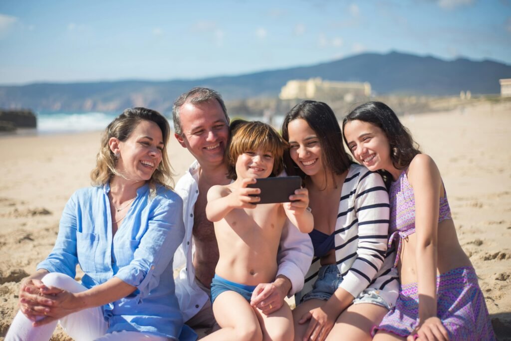 A joyful family captures a selfie together on a sunny beach day in Portugal, showcasing togetherness and smiles.